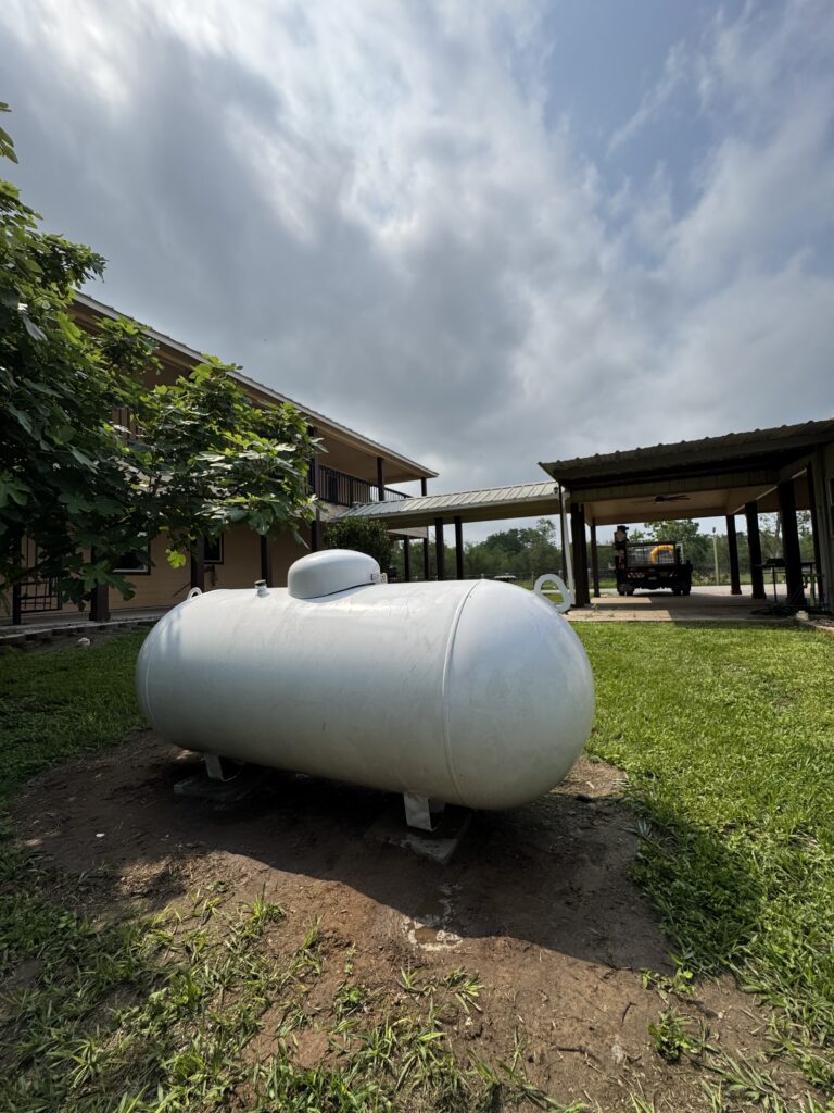 Aboveground residential propane tank installed on a Texas property near a home and covered driveway